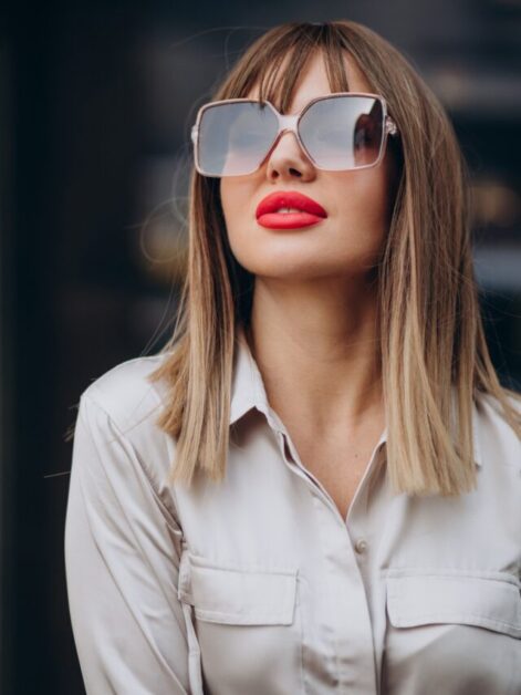 Mulher bonita de cabelos lisos, castanhos, óculos de sol e batom vermelho