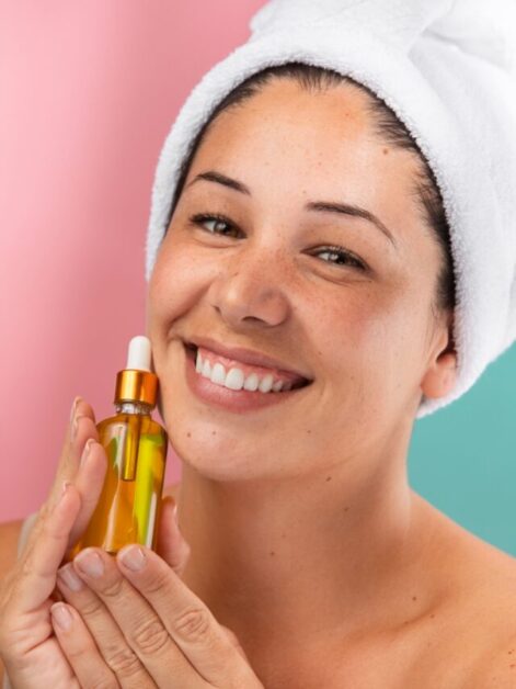 mulher hidrata o rosto com conta gotas de óleo