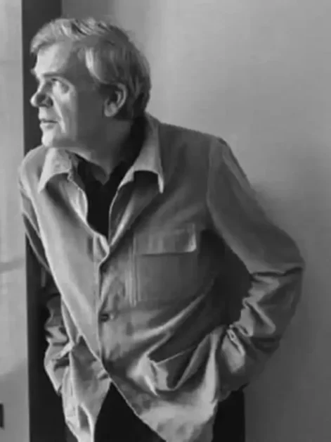 escritor Milan Kundera olha através da janela