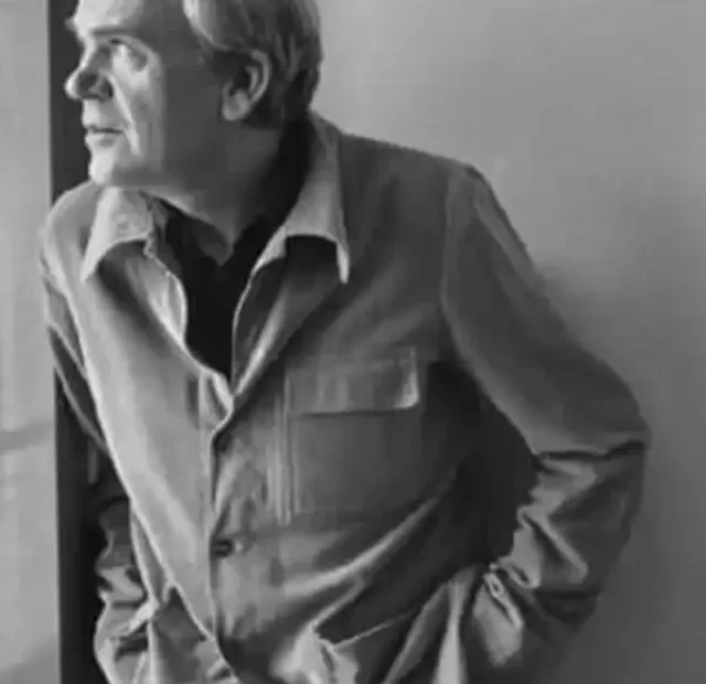 escritor Milan Kundera olha através da janela