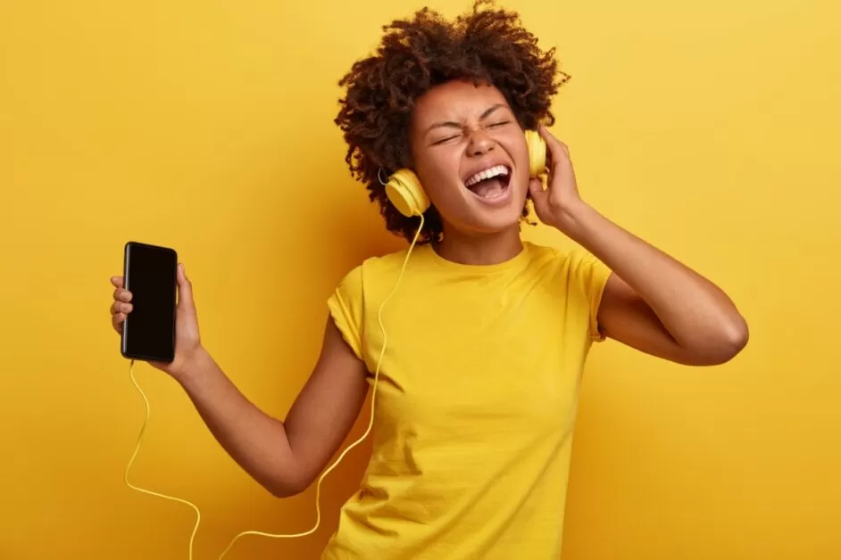 Mulher Afro escuta músicas no celular com fones de ouvido