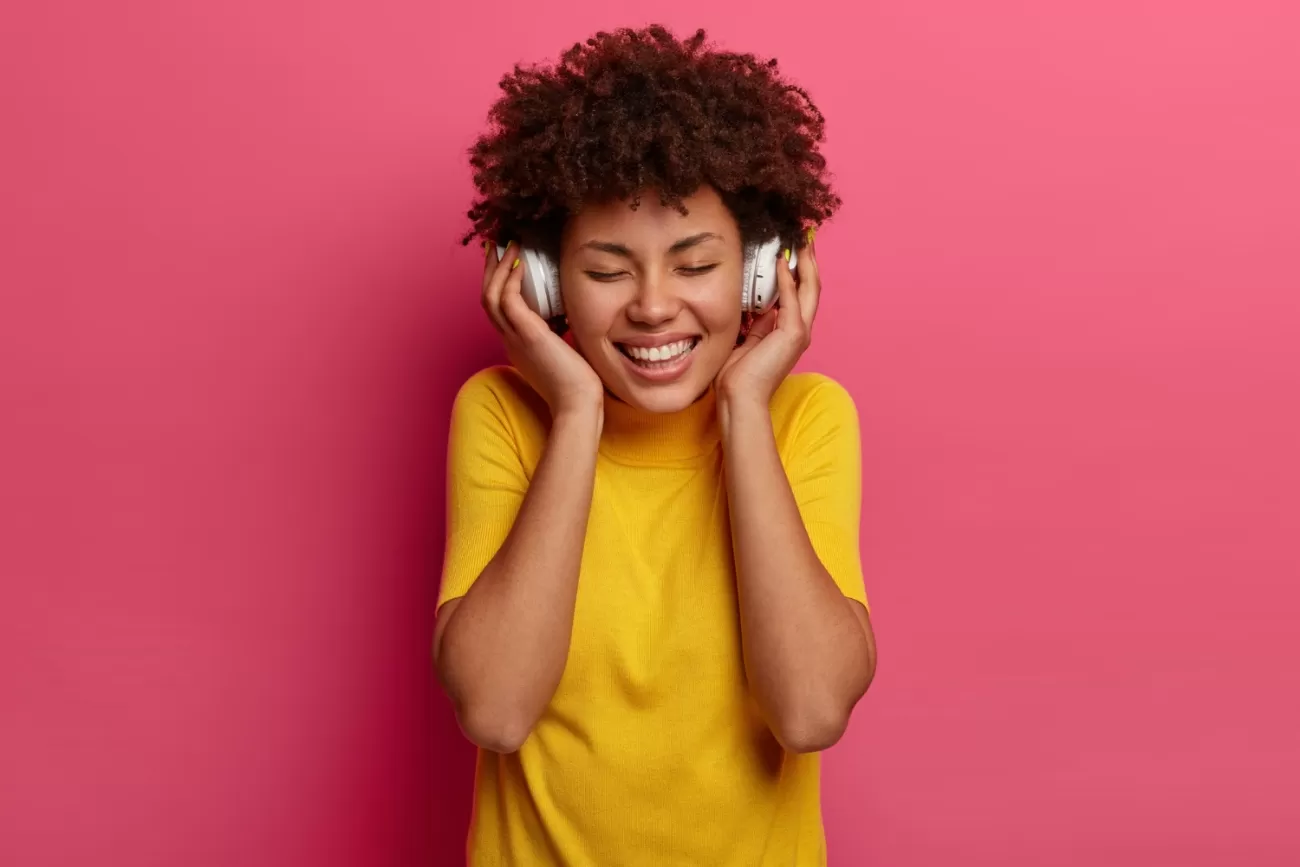 Aprenda Spotify para Iniciantes - mulher com as duas mãos segurando fones nos ouvidos
