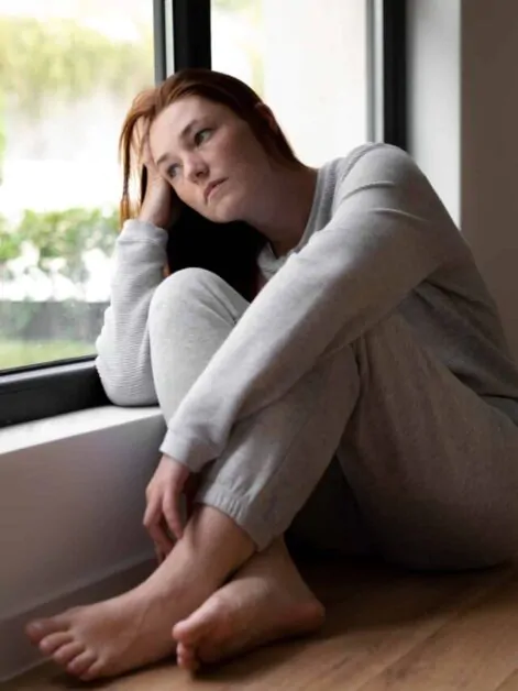 Mulher triste e pensativa sentada perto da janela