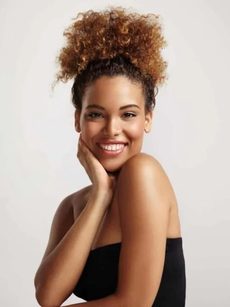 Mulher afro sorri mostrando a pele super hidratada e bem cuidada.