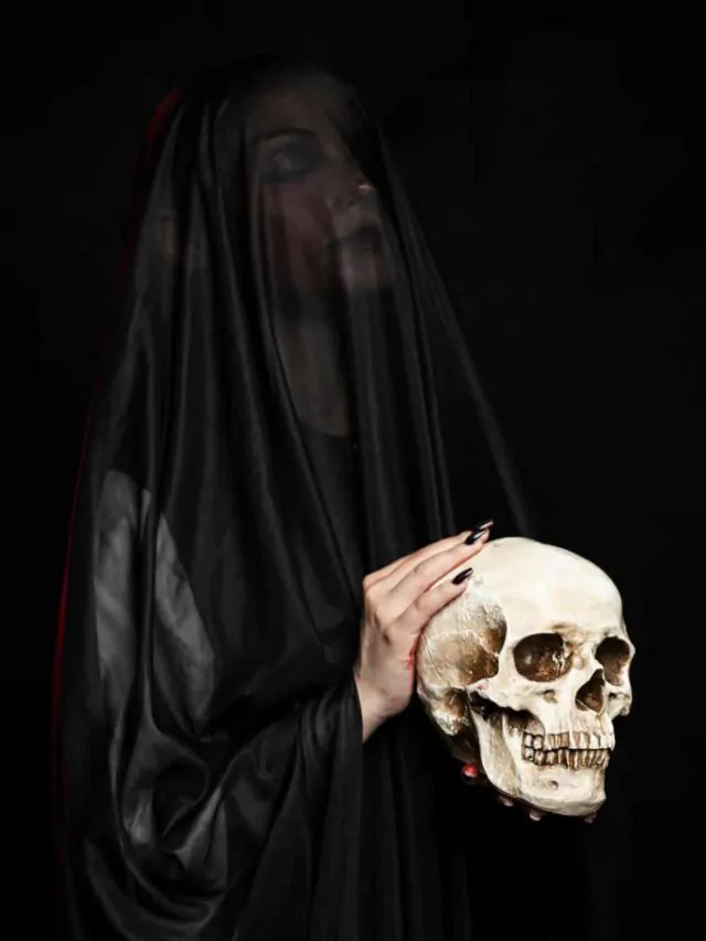 mulher veste véu preto e segura um crânio