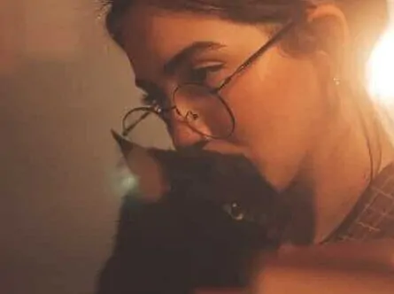 Mulher abraça um gato enquanto lê um livro e reflete se existe uma forma correta de pensar. 